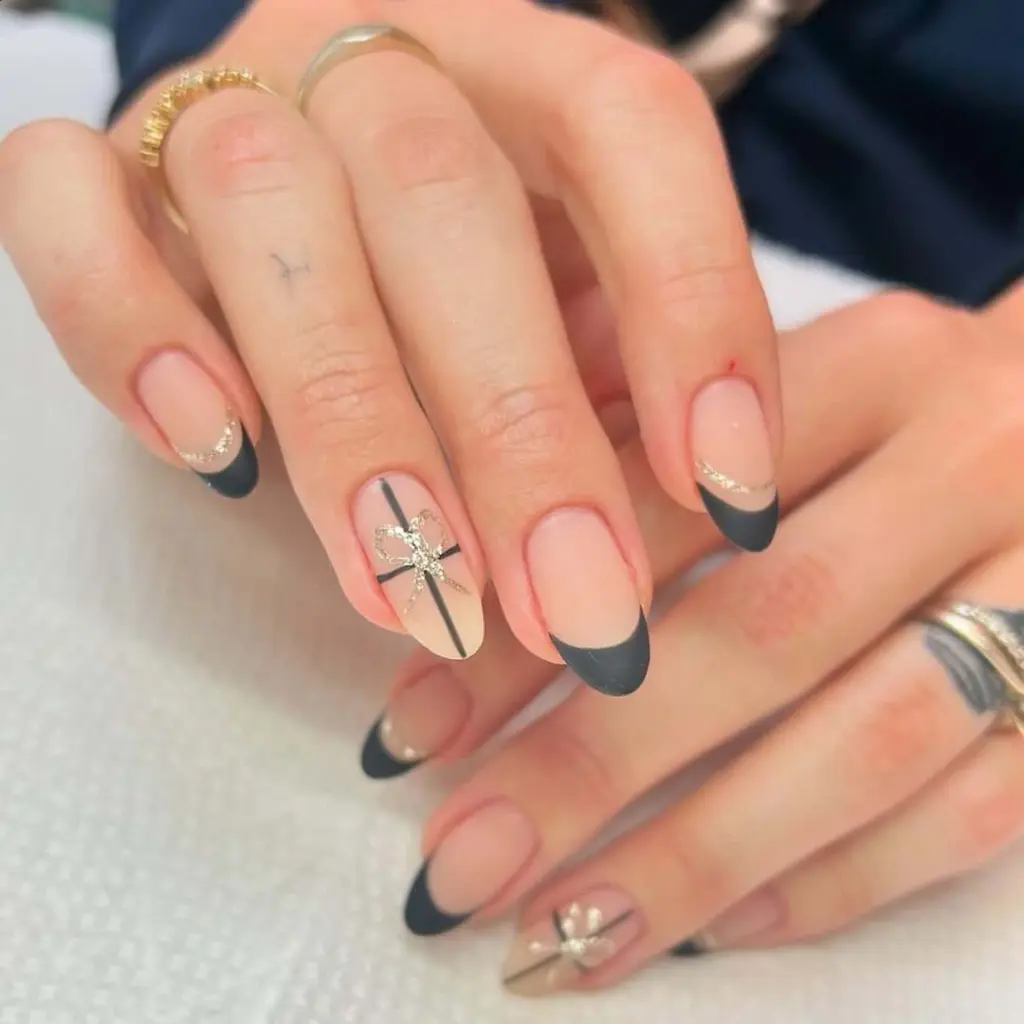 Black french tips with rhinestone bow accent nail design