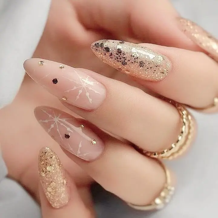 Gold glitter and white snowflake nail art on nude base for new years design