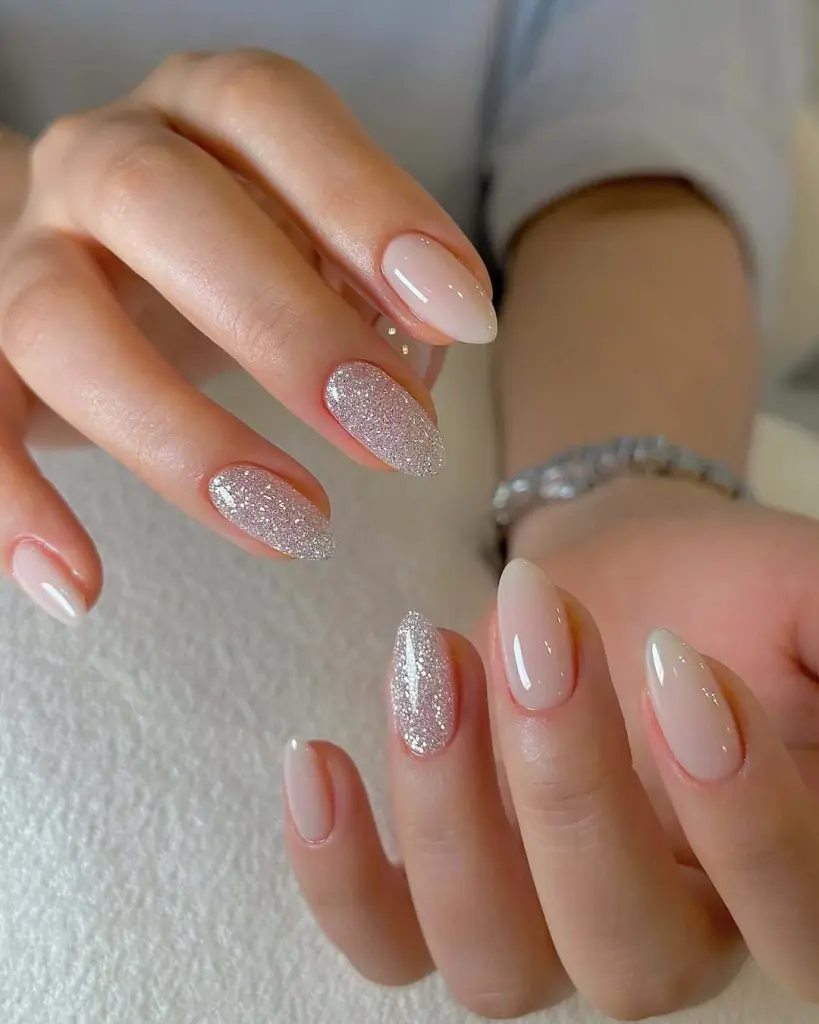 Alternating silver glitter and glossy nude almond nails new years design