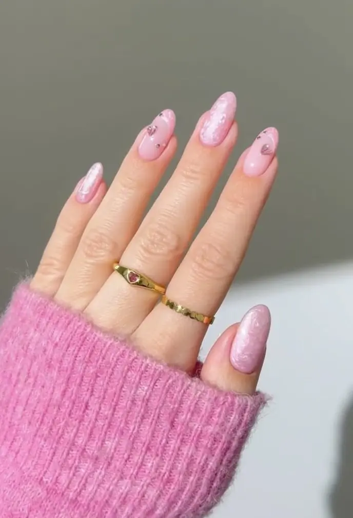 Pink almond nails with pearlescent finish and scattered rhinestones