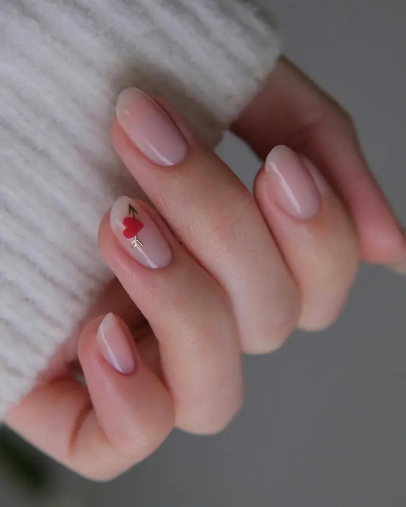 Pink glazed nails with single red heart accent and almond shape