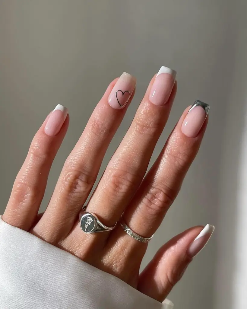 Nude pink nails with silver outlined hearts and metallic French tips
