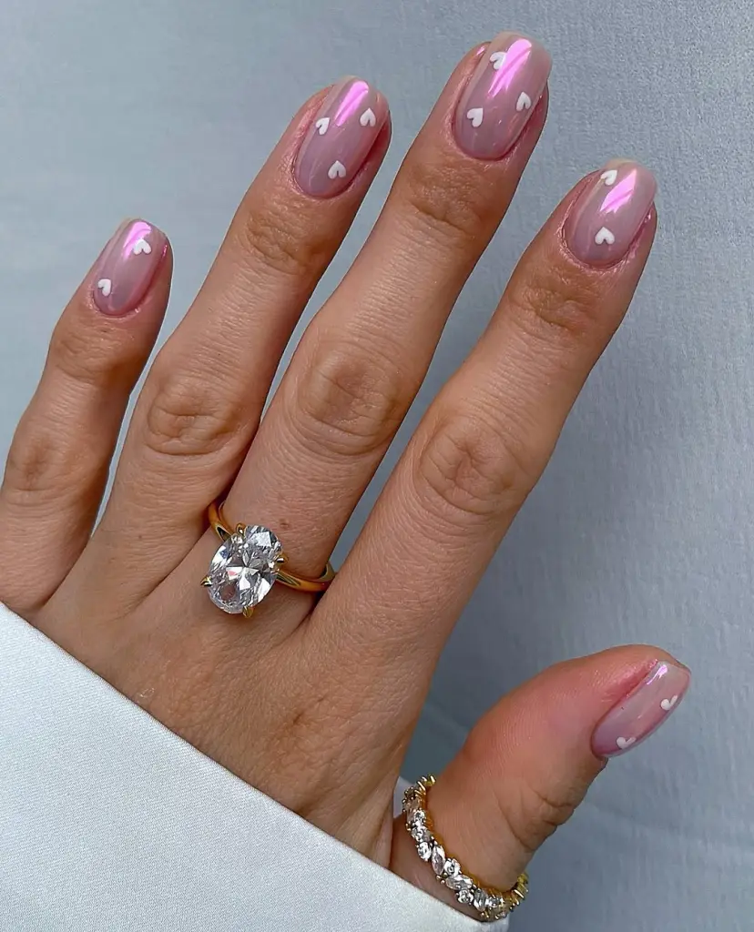 Short chrome pink valentine nails with white heart designs
