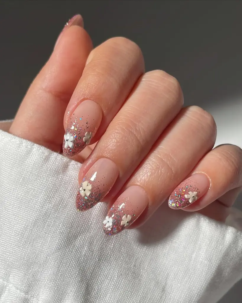 Almond spring nails with nude to glitter ombre and white floral stickers
