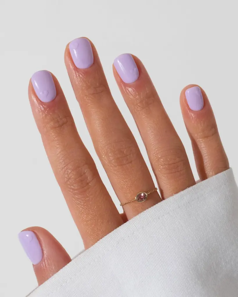 Short lavender nails with embossed heart designs
