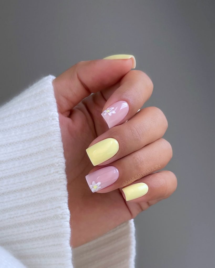Alternating pink and yellow nails with white floral details
