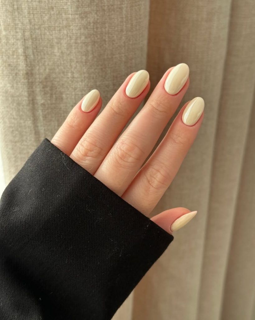 Elegant almond nails with vanilla chrome polish creating a soft shimmer effect