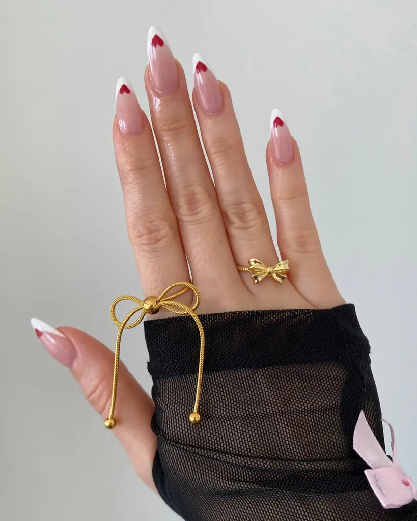 Almond nails with white French tips and tiny red hearts