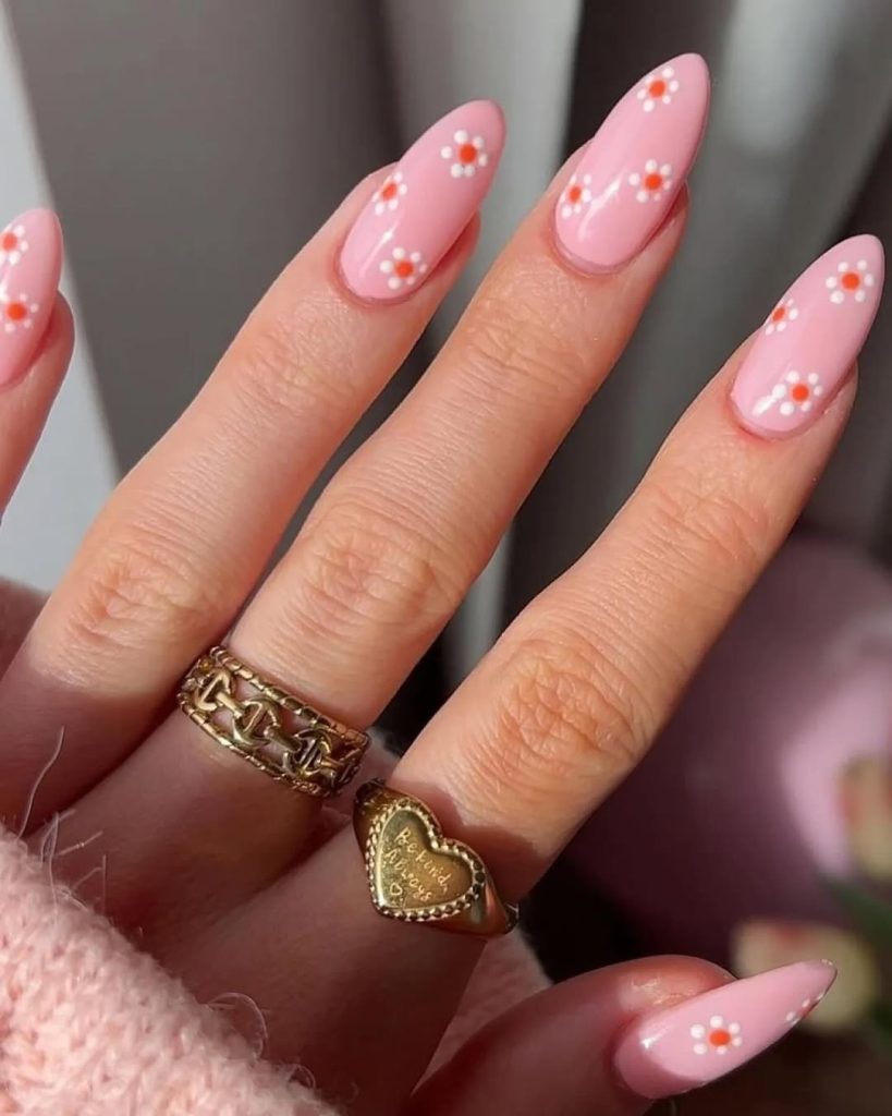 Almond spring nails with pink base and small white and orange daisy nail art design
