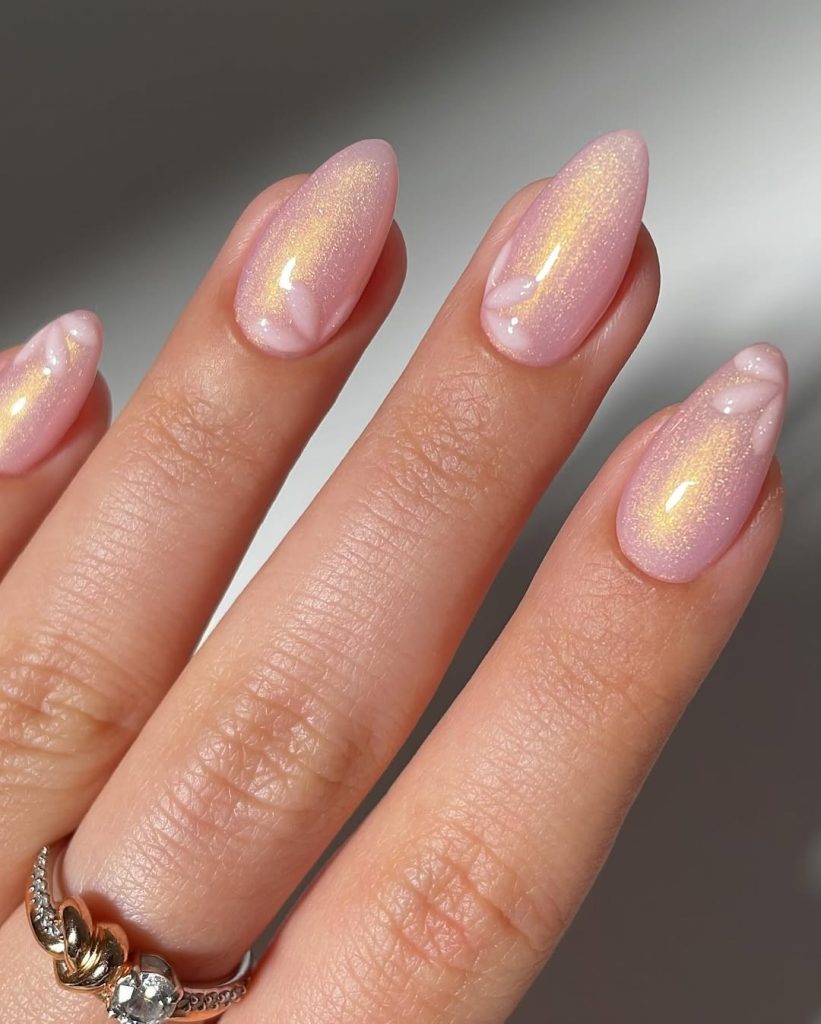 Shimmery pink almond nails with white floral tips and gold reflect
