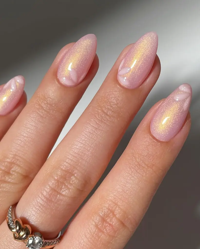 Shimmery pink almond nails with white floral tips and gold reflect
