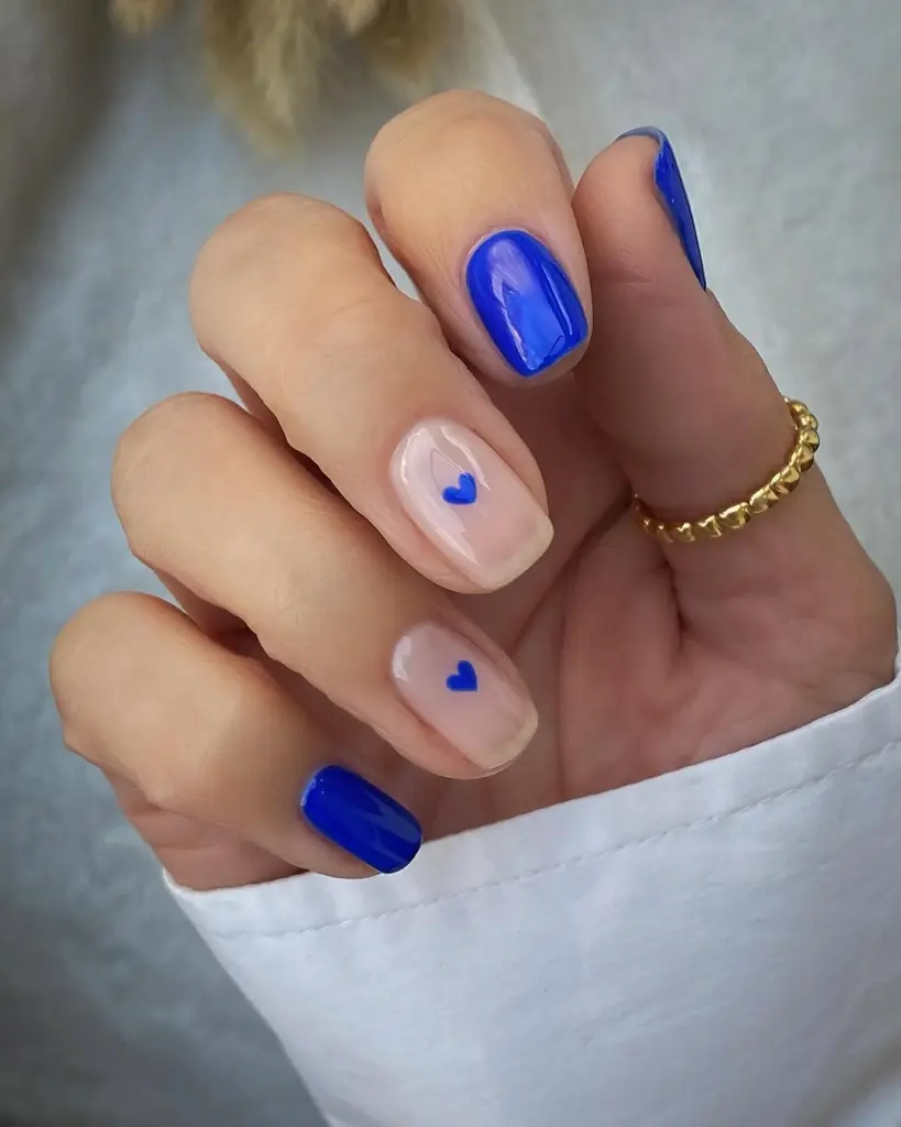 Nude nails with electric blue hearts and accent nails