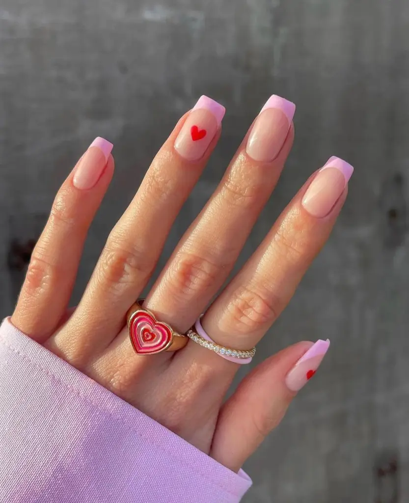 Long square nails with pink French tips and red heart detail on one nail