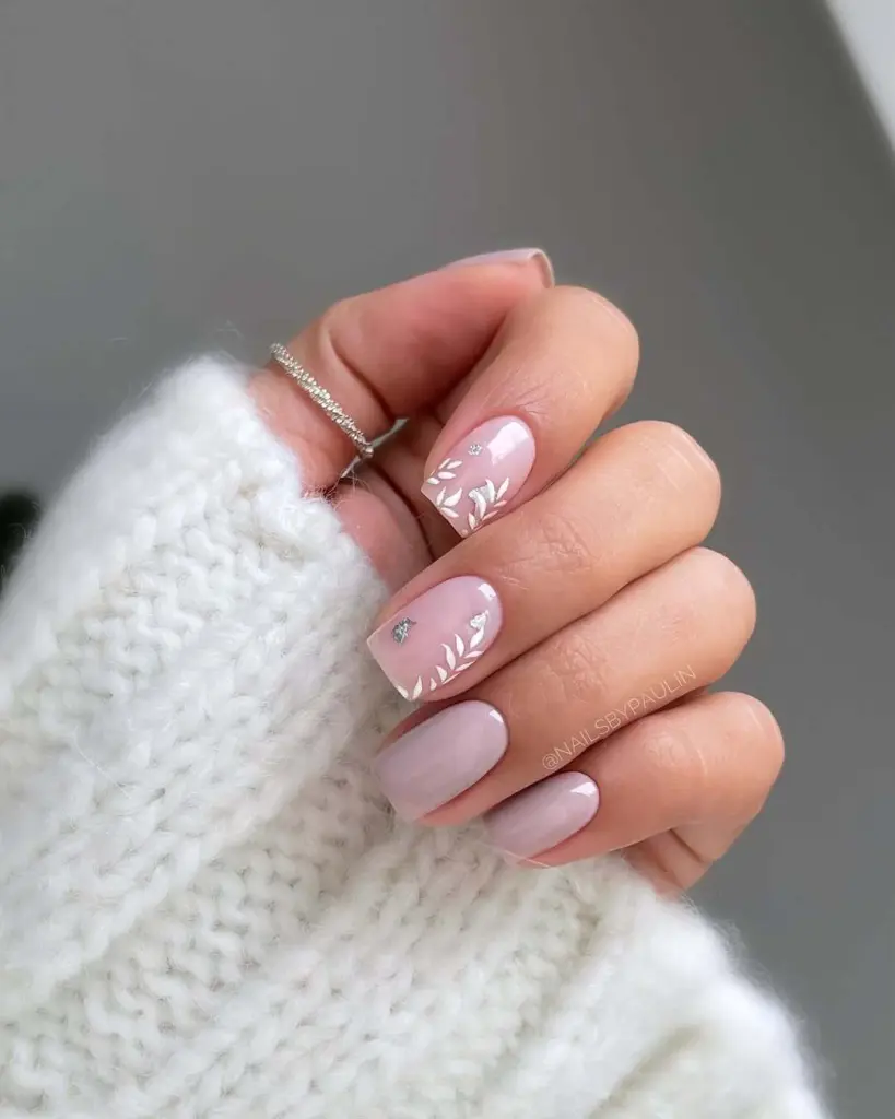 Pink nails with white leaf art and crystal accents