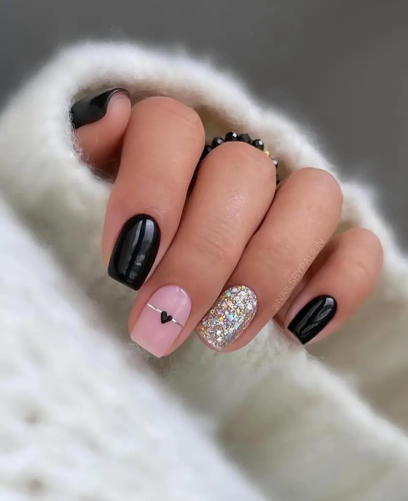Short black and pink nails with heart detail and silver glitter accent
