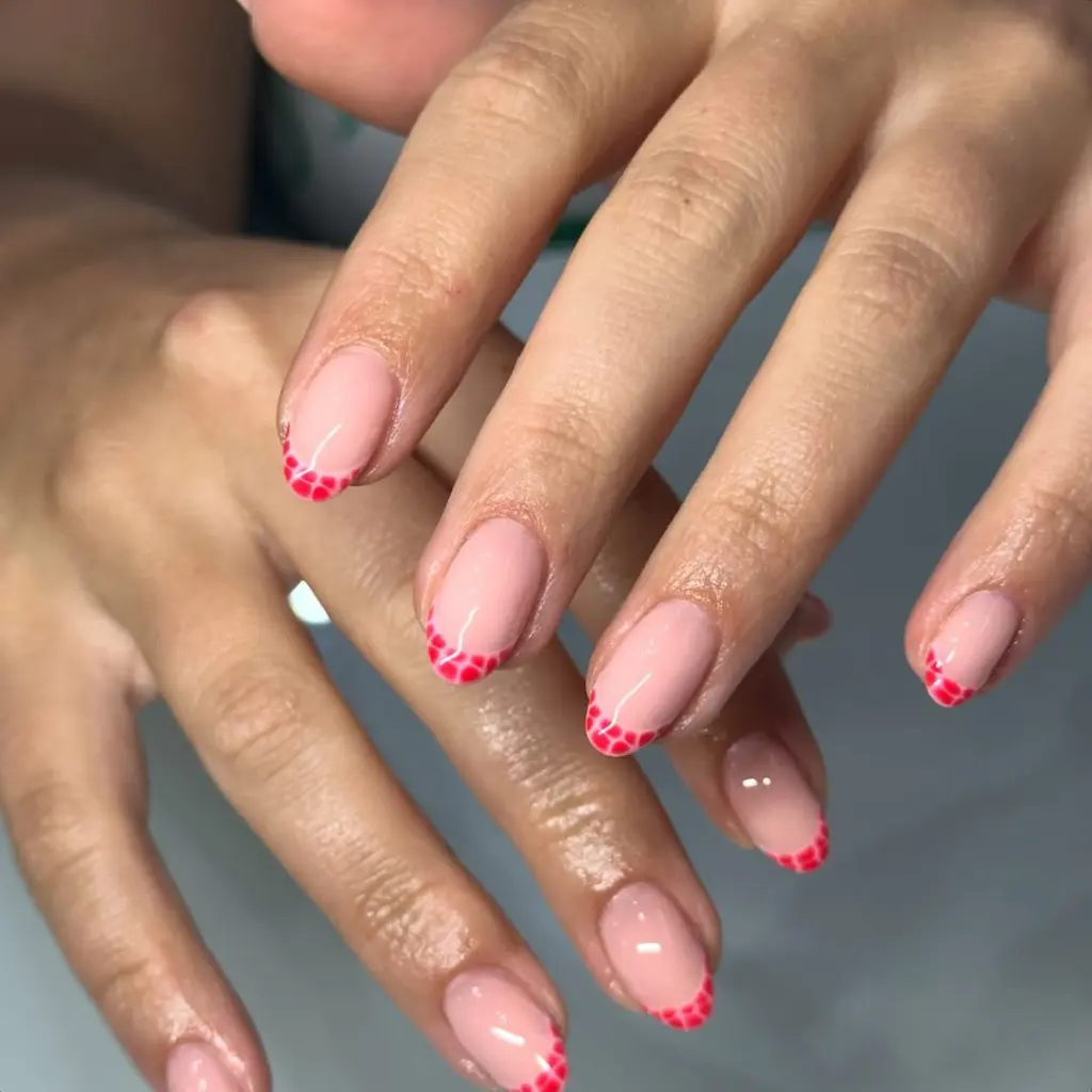 Oval nails with light pink base and red dotted French tips