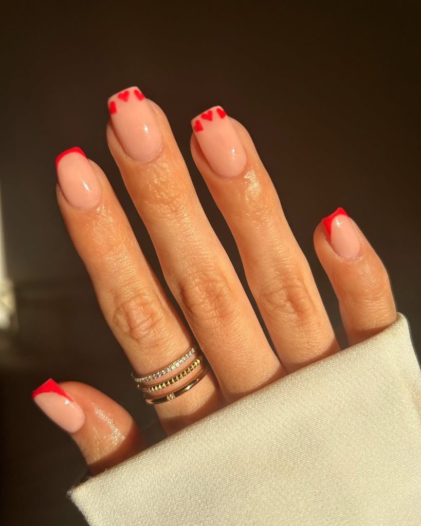 Nude almond nails with red heart French tips