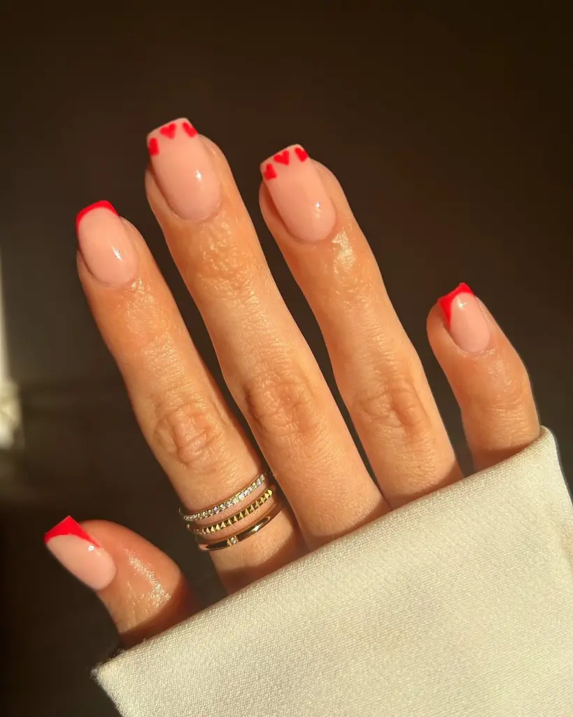 Nude almond nails with red heart French tips