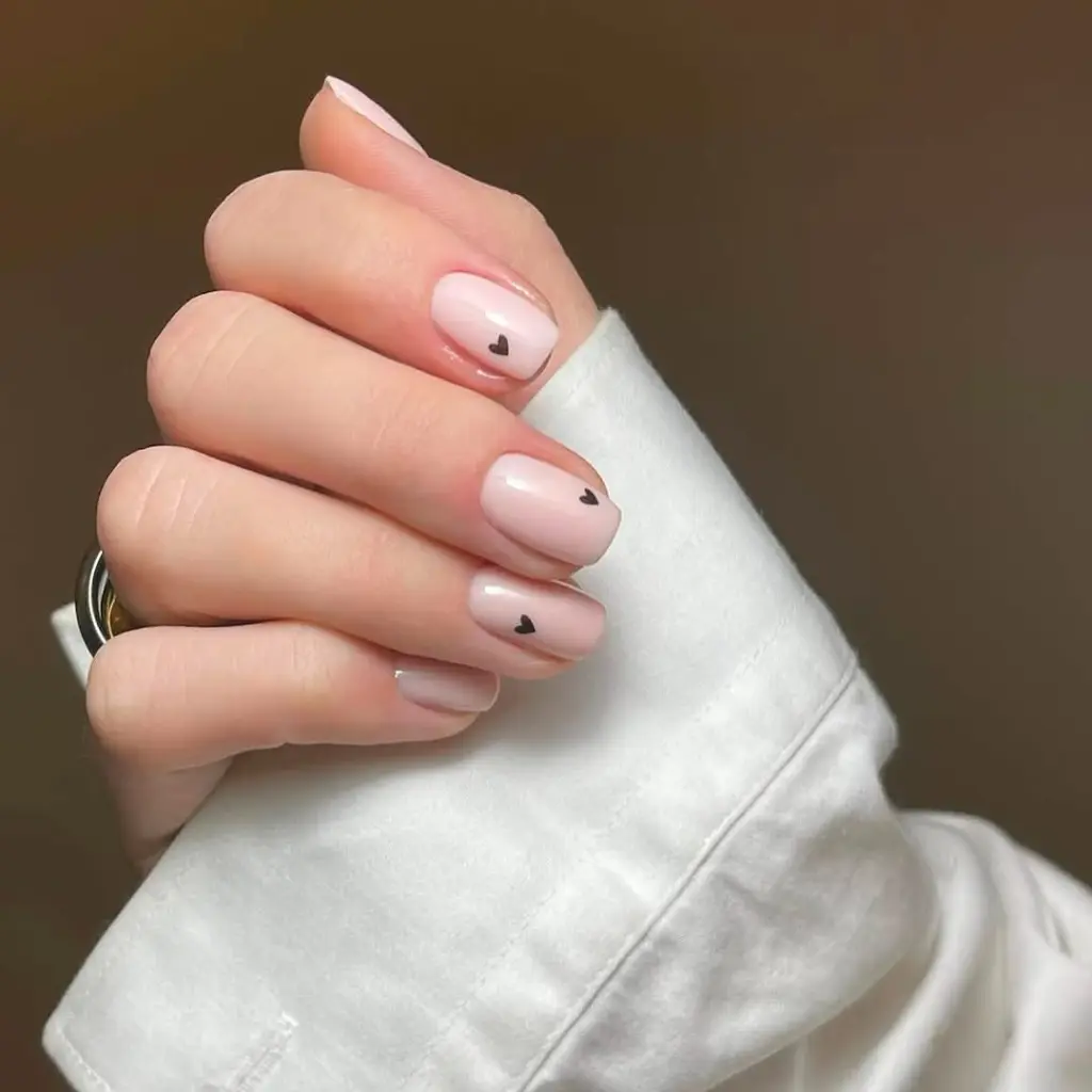 Short square nails with neutral beige polish and black micro heart details