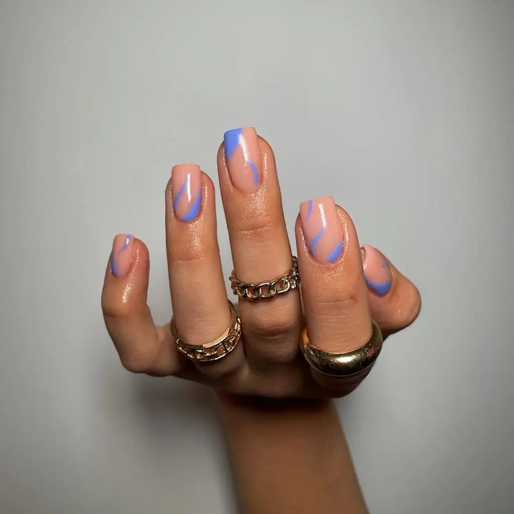 Classy square nails with nude base and abstract blue curved swoops
