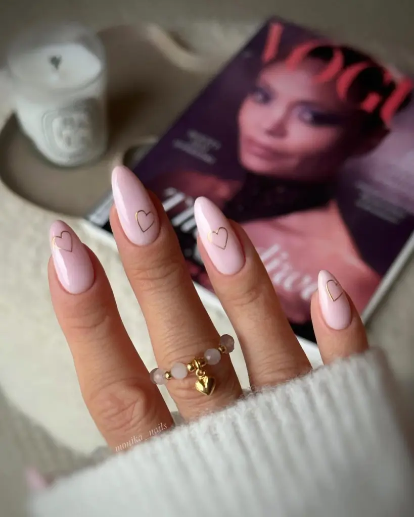 Long almond nails with sheer pink base and thin metallic heart outlines
