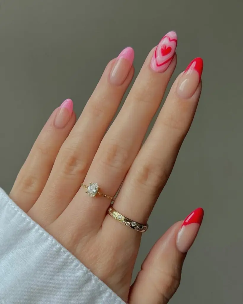 Valentine's Day manicure featuring sheer nude base with red French tips and pink swirled heart accent nail
