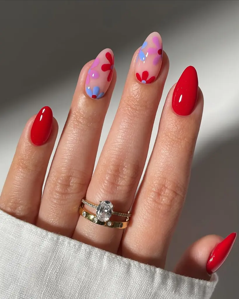 Sheer Pink spring nails with red flowers and blue floral accents alternating with solid red nails
