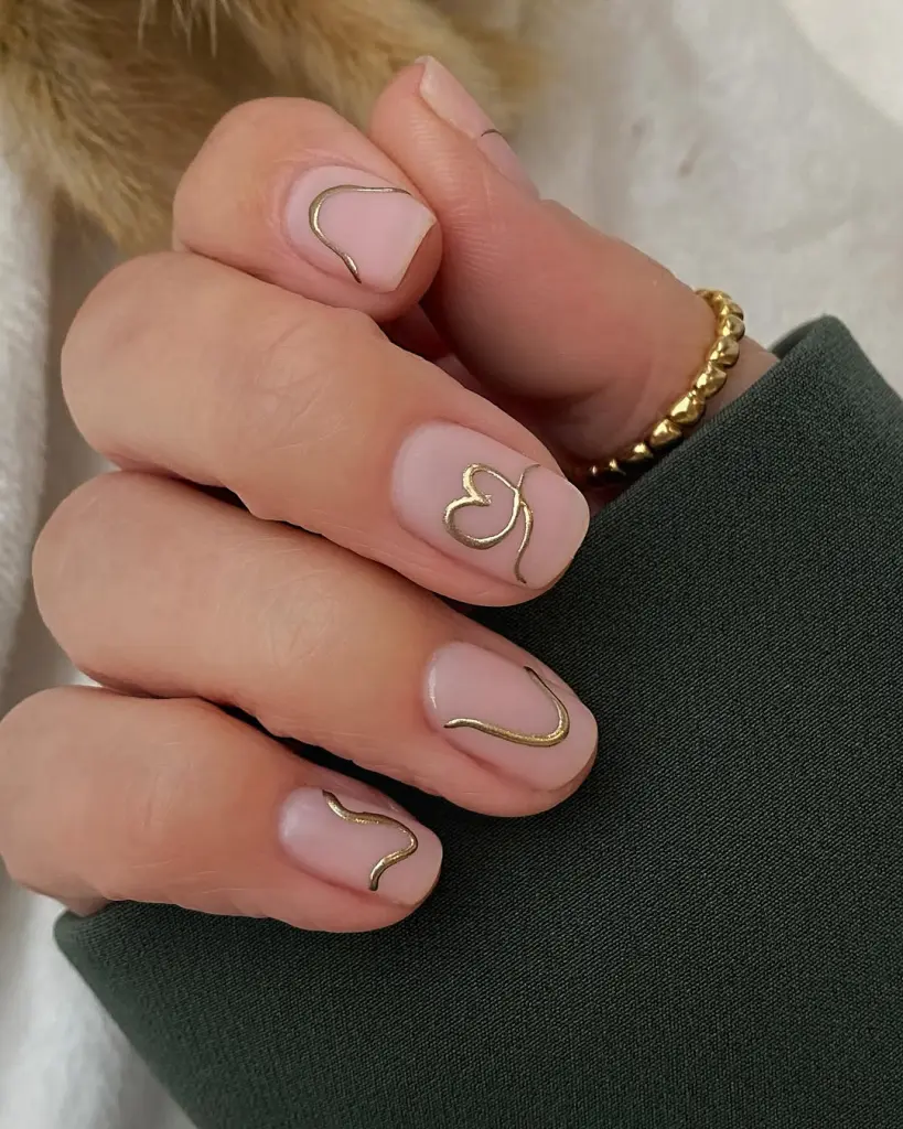 Sheer nude nails with gold chrome heart outlines and almond shape
