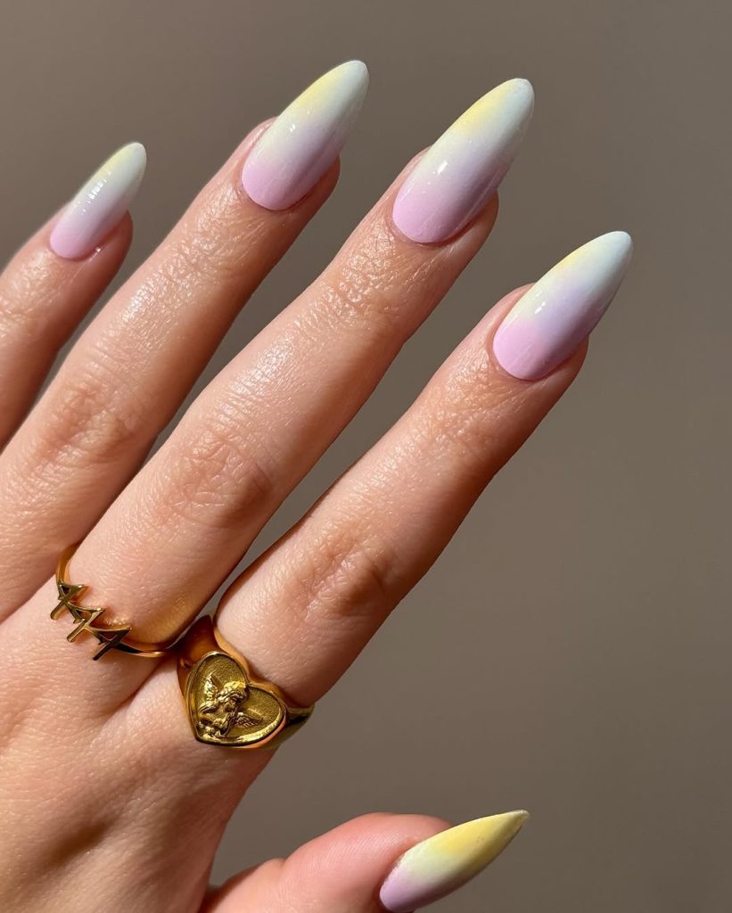 Long almond nails with ombré design fading from yellow to pink to white

