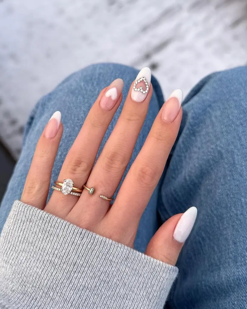 White French tips Valentine day nails with negative space heart crystals and almond shape