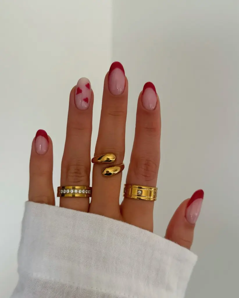 Short oval nails with alternating french tips and sheer polish with heart accents