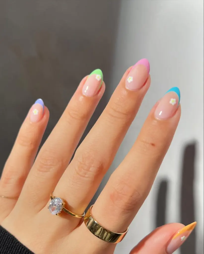 Almond nails with sheer pink base and multicolor pastel French tips with matching daisy accents