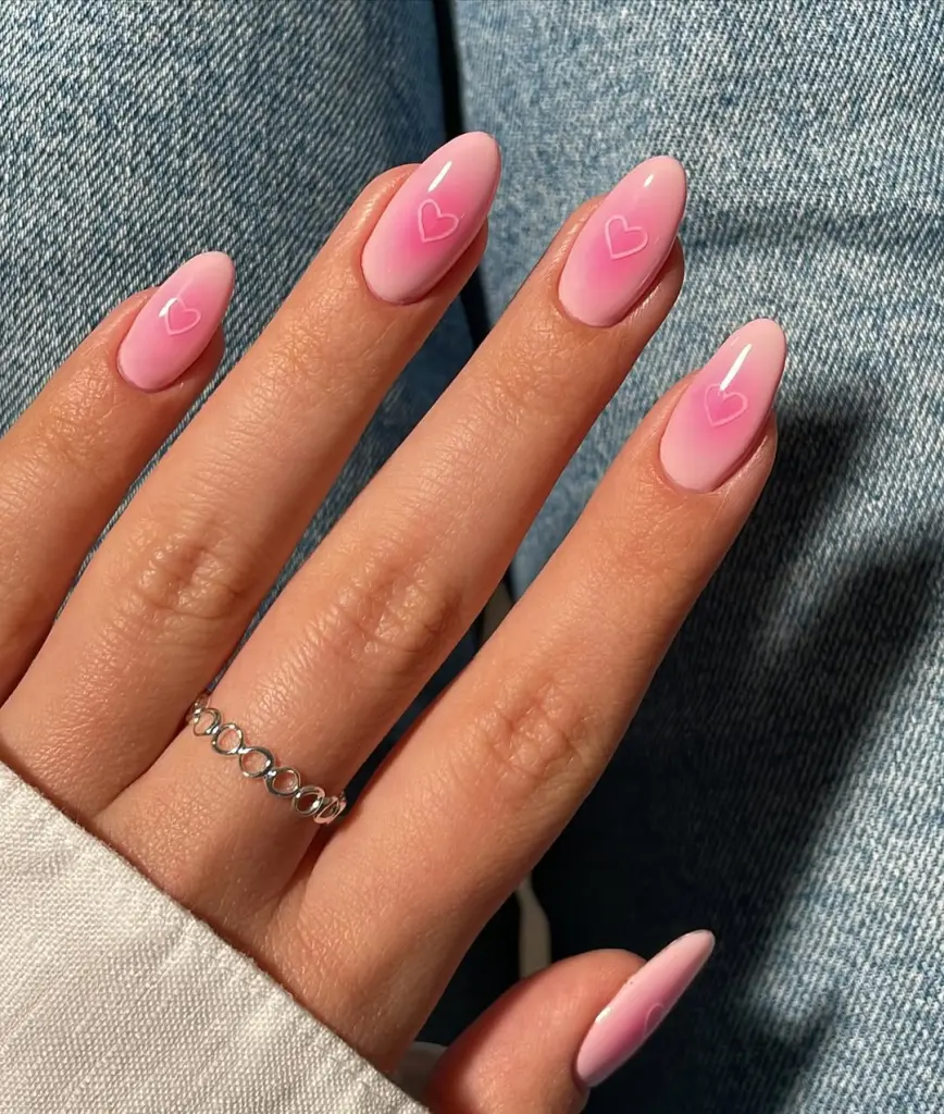 Pink gradient Valentine nail design with white heart outlines and almond shape