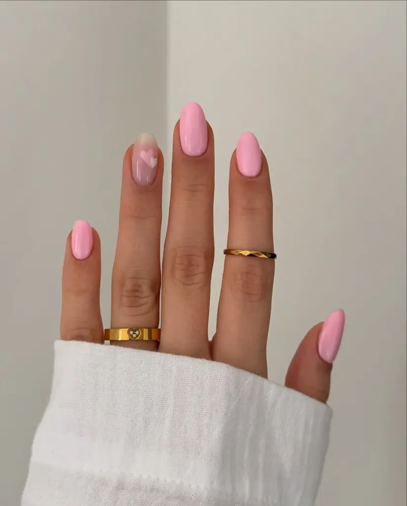 Short oval nails in solid pink with one sheer heart accent nail