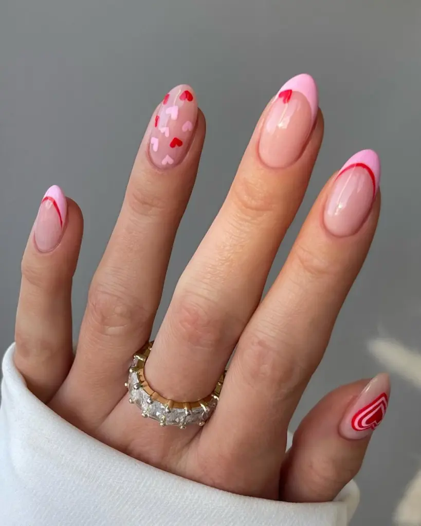 Pink French manicure with curved tips, red heart accent nail, and swirl design