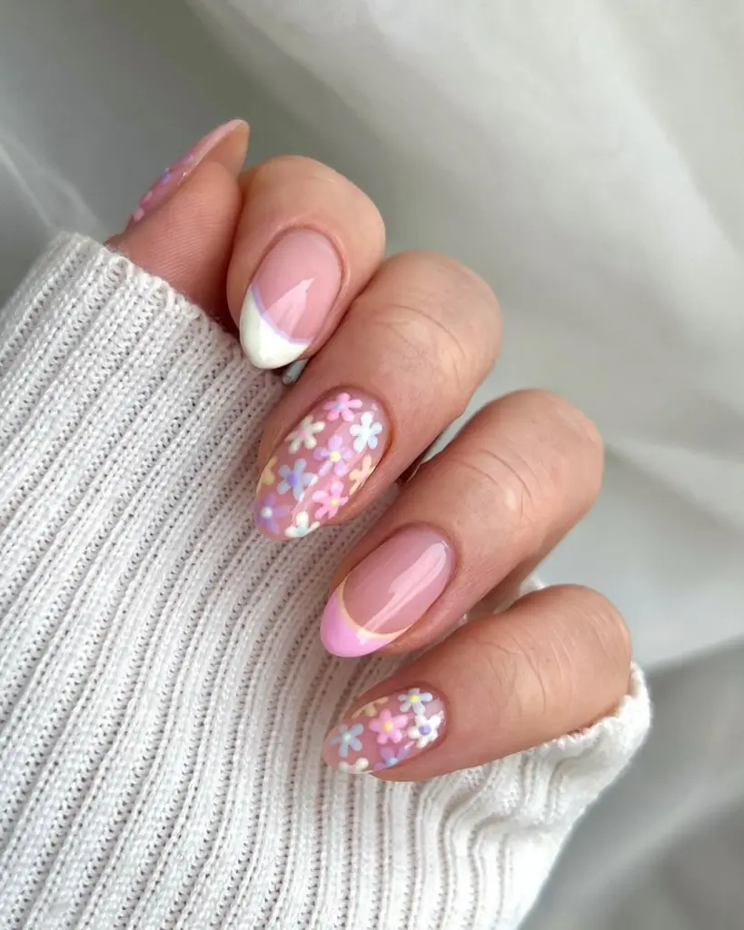 Spring nails with pink and white curved French tips and pastel flower confetti accent nails
