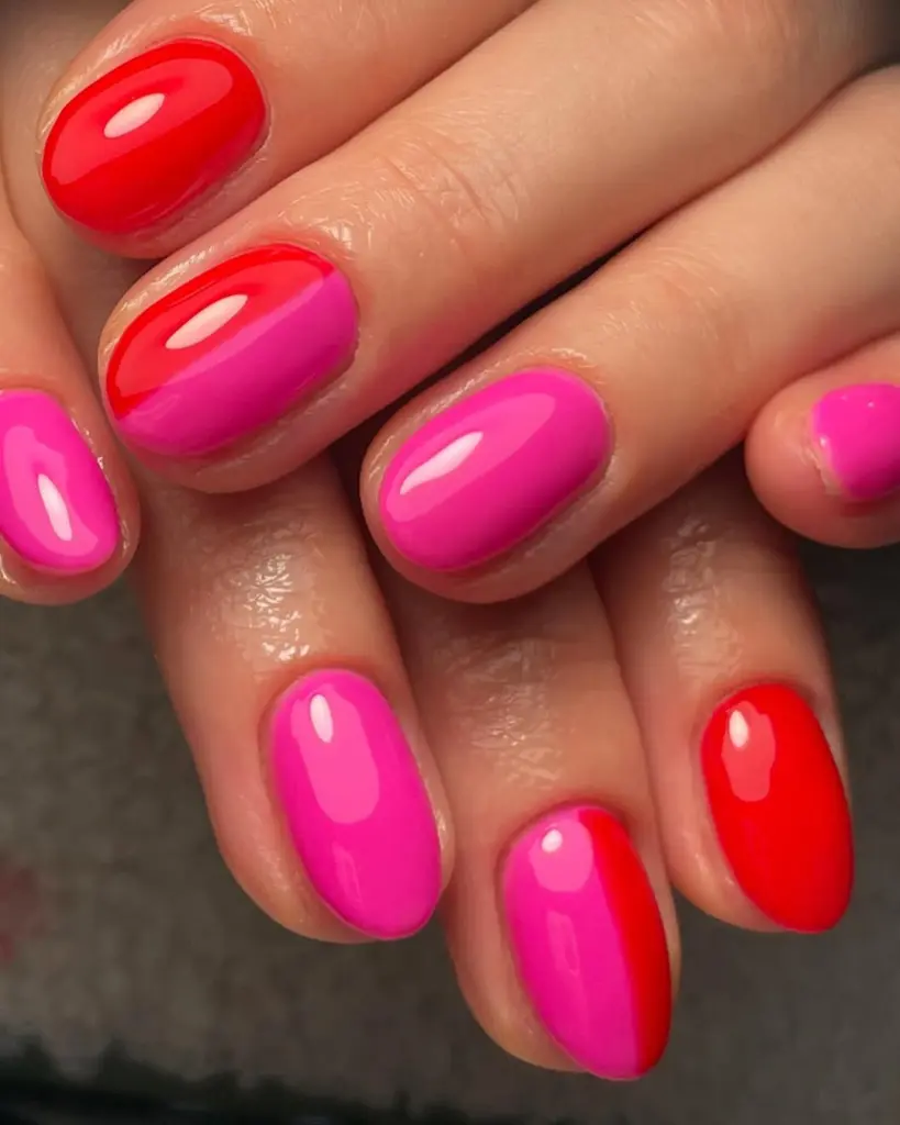Short oval nails painted in alternating solid hot pink and bright red polish