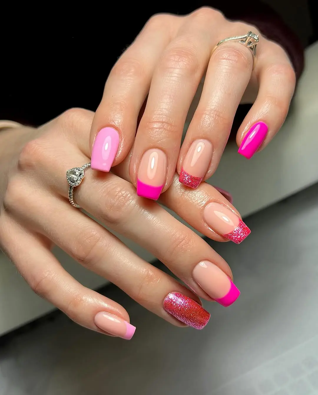 square pink nails with nude base, hot pink French tips and pink glitter accents