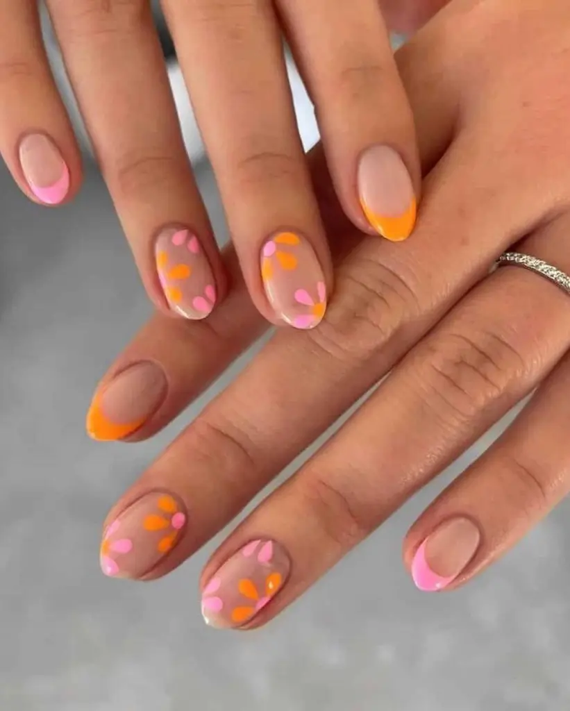 Sheer nude nails with orange and pink floral details and matching French tips
