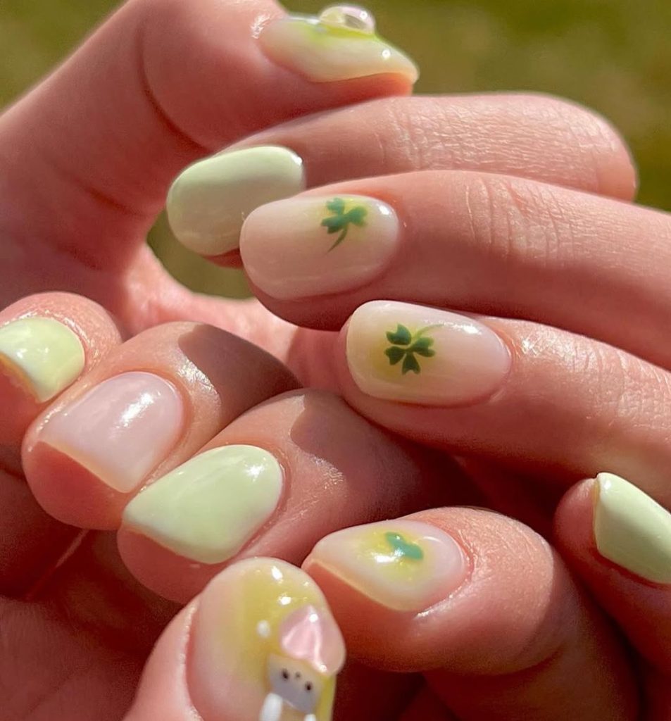 St Patrick's Day short nails with alternating nude and mint green polish, small shamrock nail art accents