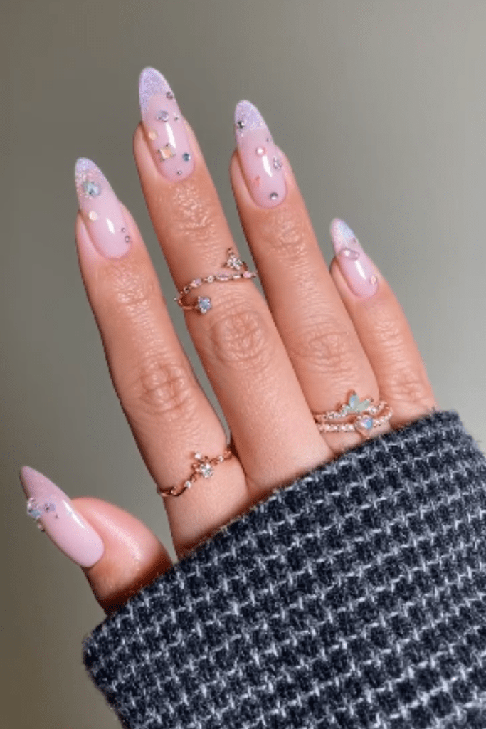 Almond spring nails with iridescent pink polish and scattered rhinestone accents