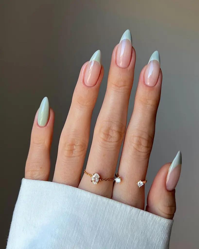 Almond shaped transparent pink nails with sage green French tips creating an elegant old money aesthetic with glossy finish