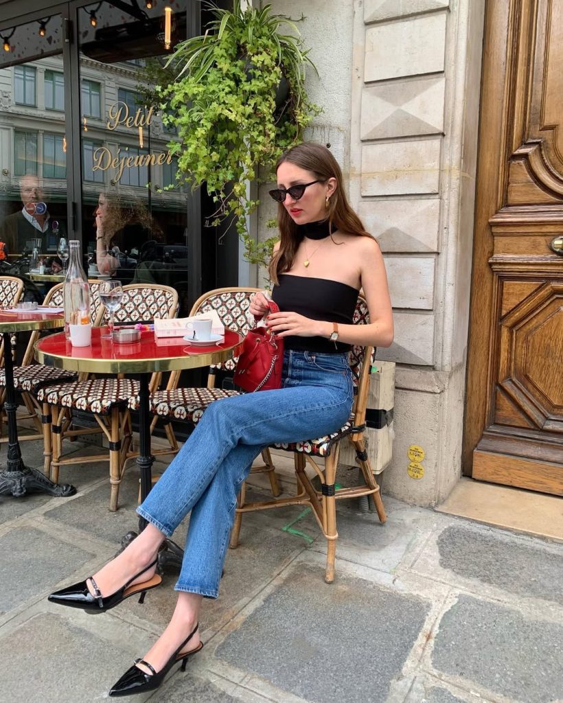 Woman at Parisian cafe wearing black tube top with high waist jeans and black slingback heels