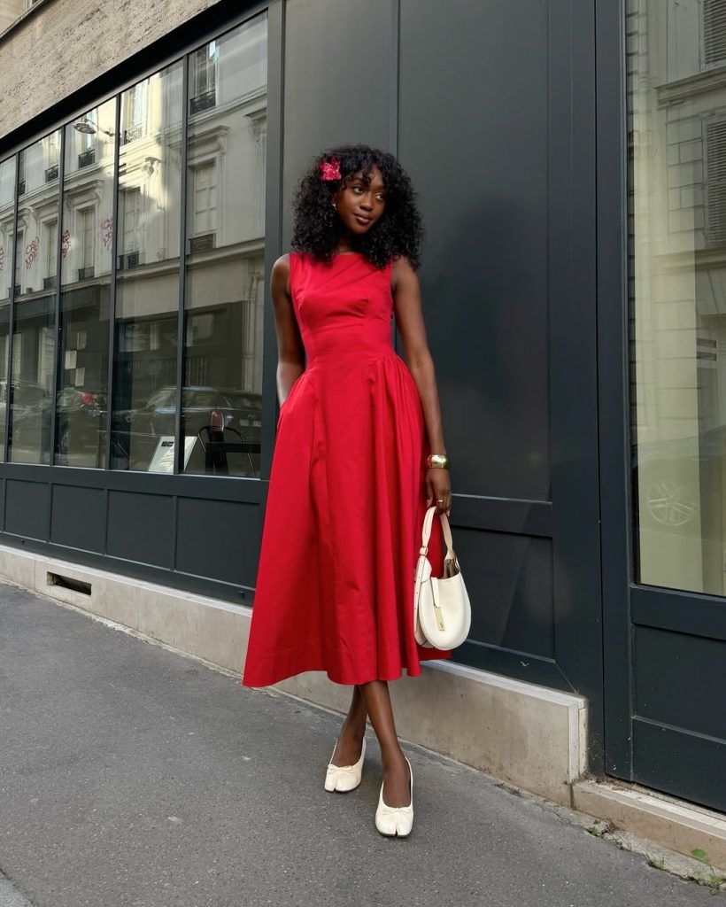 Woman in red sleeveless midi dress with cream ballet flats and white handbag
