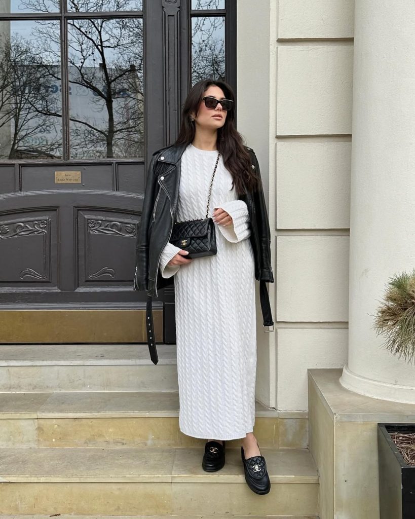 Elegant spring outfit with white cable knit maxi dress, black leather jacket, designer loafers and quilted crossbody bag

