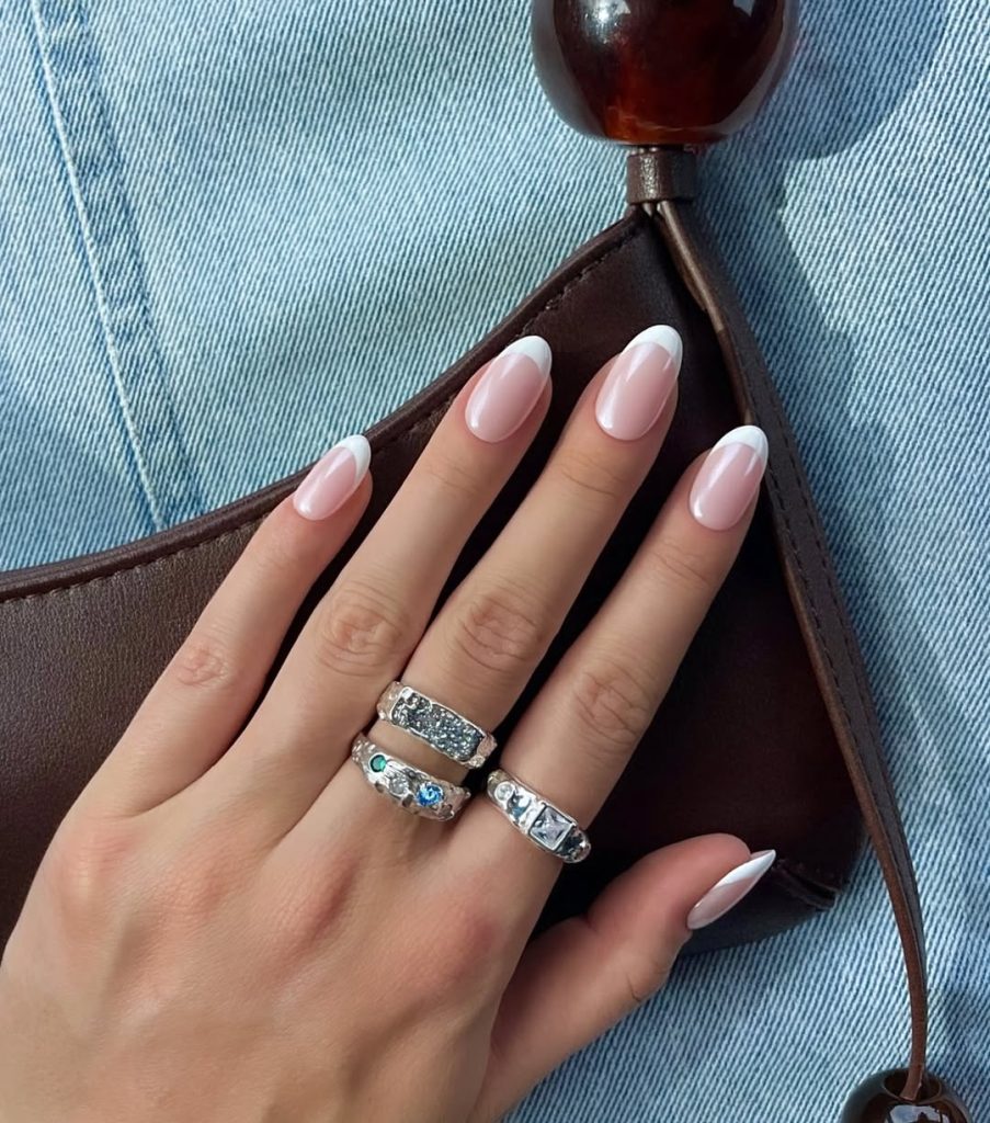 Almond shaped pink nails with glossy white French tips and glazed finish 