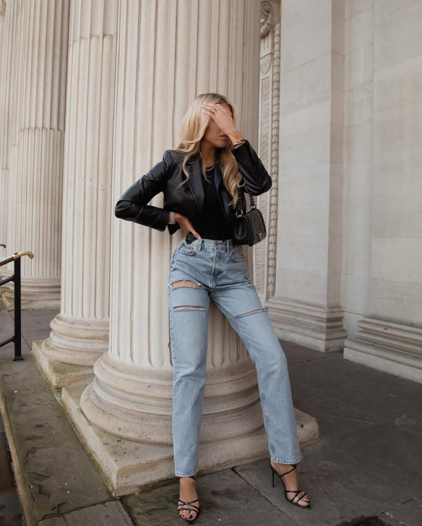 Woman in black leather jacket and ripped jeans with strappy heels 