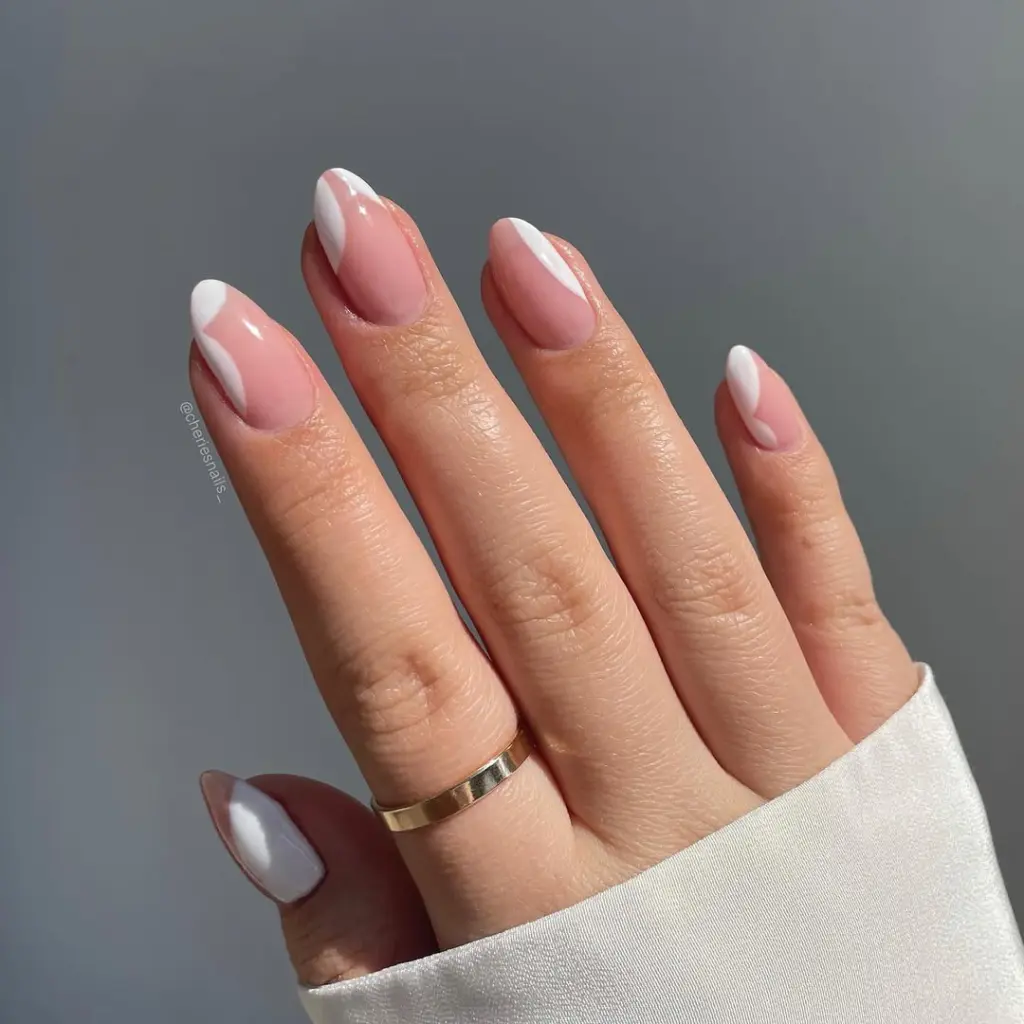 Almond shaped pink nails with artistic white negative space designs creating a modern spring old money manicure