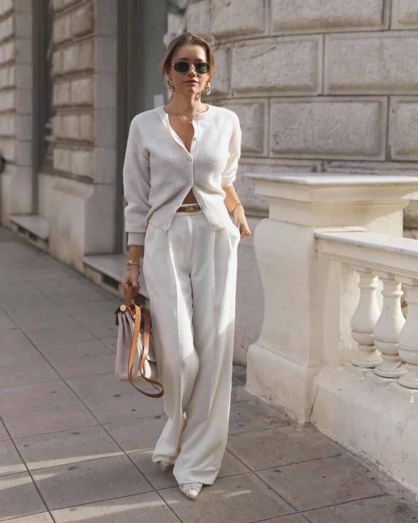 Elegant spring outfit with cream ribbed cardigan, white wide-leg dress pants, snakeskin pointed flats, gold accessories and canvas tote bag with leather strap