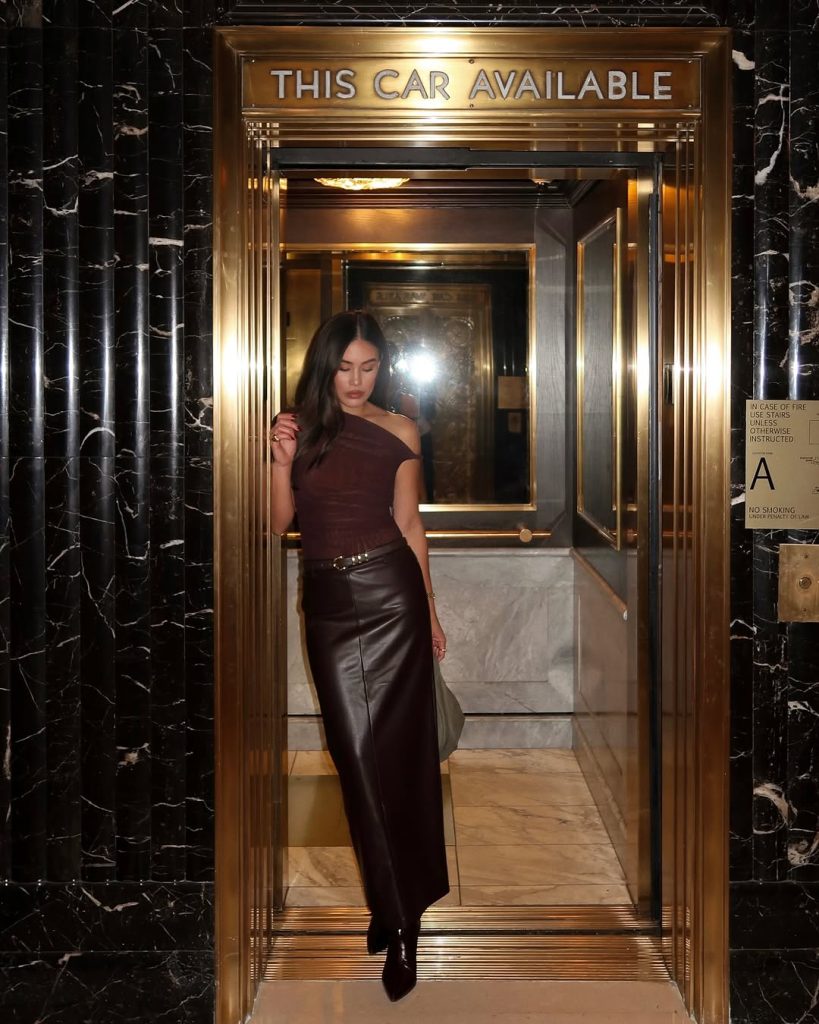 Woman in burgundy one shoulder top and leather maxi skirt
